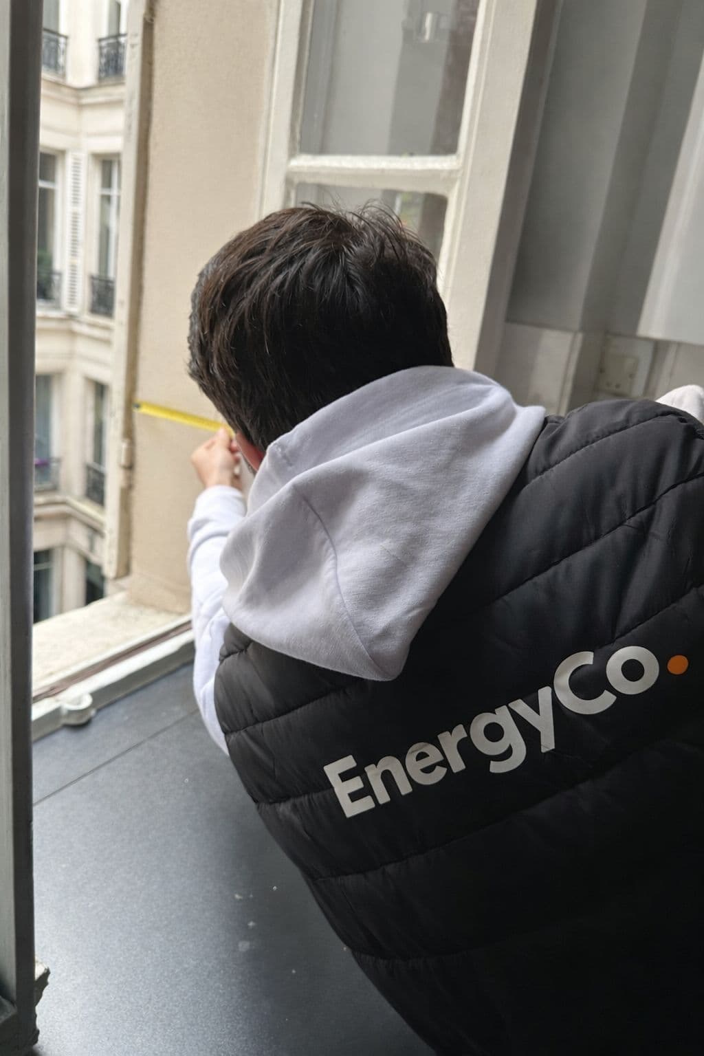 Technicien EnergyCo prenant une mesure à une fenêtre parisienne
